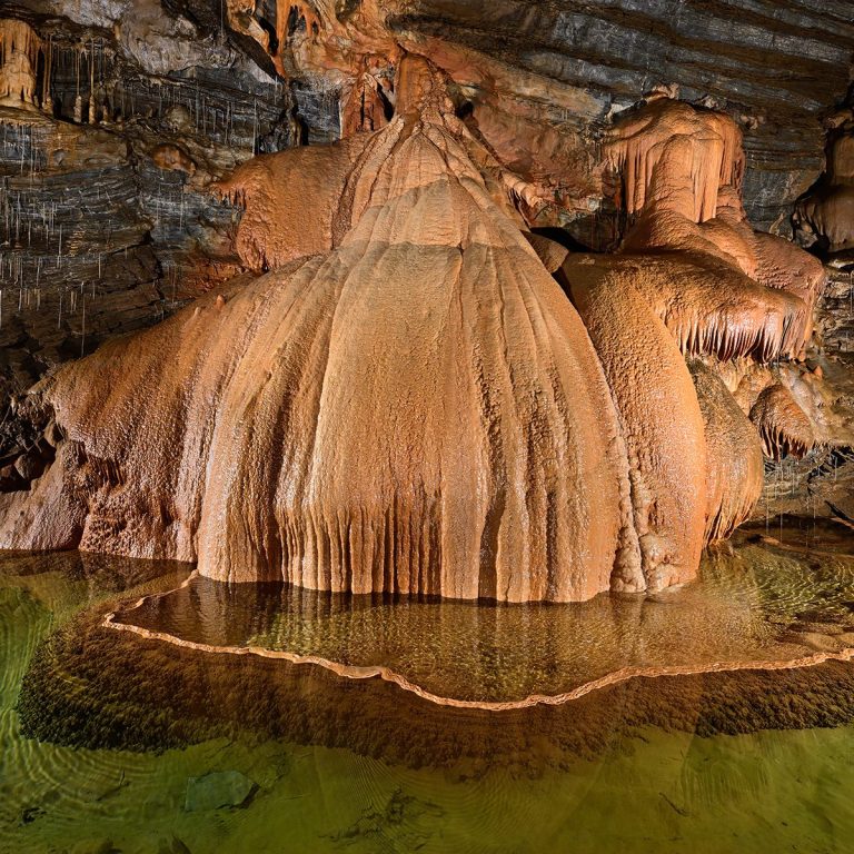 concretion geante en draperie ocre et bassin d eau cristalline au gouffre geant de cabrespine