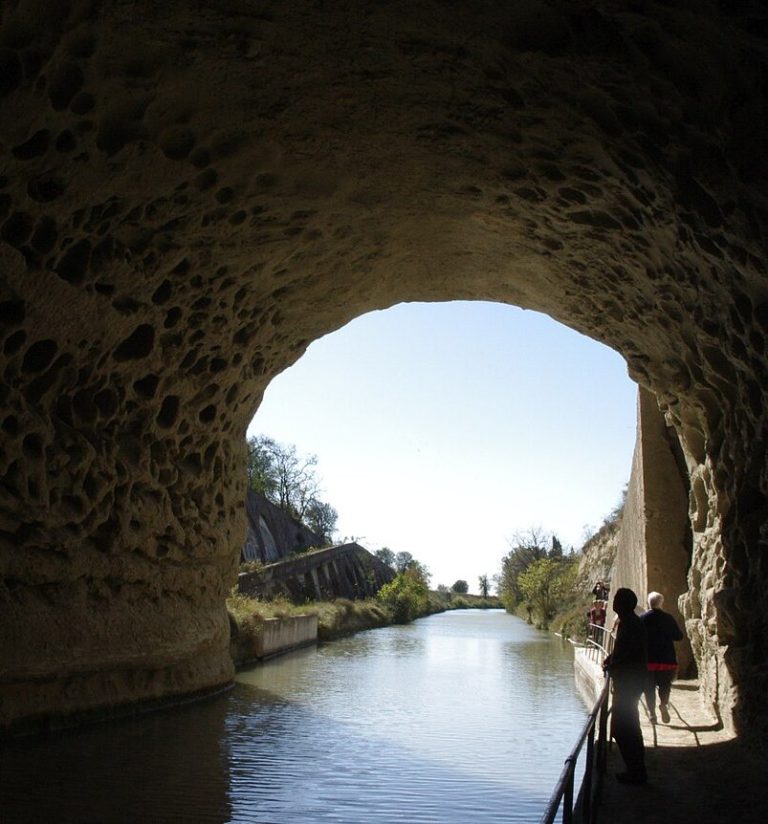 l'arche d'entrée en pierre de taille du Tunnel du Malpas reflétée dans l'eau calme du Canal du Midi